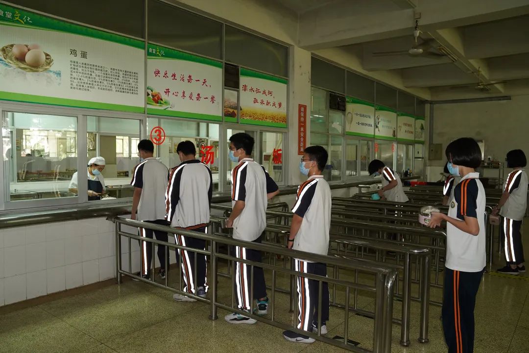 湖景中学食堂地砖上贴着标识语,提醒用餐学生"保持1米安全距离",该校